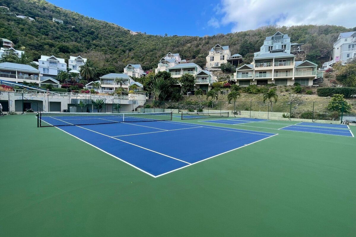 Blue tennis playing area inside a green out-of-bounds surround with white lines, the blue on green scheme used at the US Open, built by Precision Sports CT